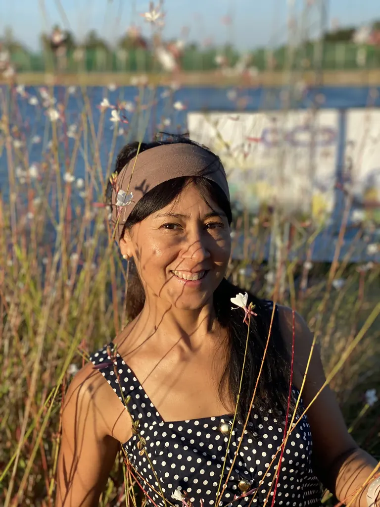 La Lidia Amaya somrient entre les flors, al costat del riu