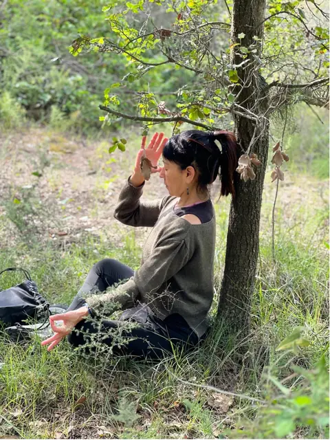 La Lidia Amaya meditant sota un arbre, al bosc